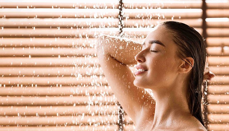 kobieta myjąca włosy pod prysznicem szamponem nawilżającym